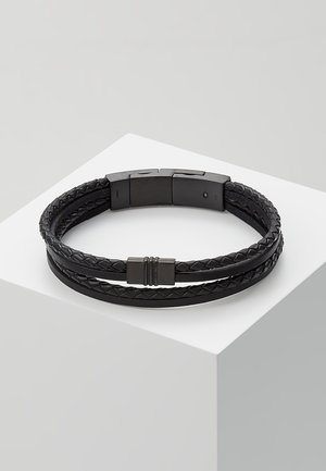 Bracelet en cuir noir tressé avec fermoir magnétique, présentant deux fines lanières de cuir et une lanière tressée dans un design minimaliste.