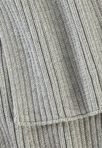 Tissu tricoté gris clair avec une texture côtelée verticale, offrant une apparence douce et des couture régulières. Le matériau est épais et confortable.