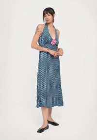 Modré a čierne šaty s halter krkom a károvaným vzorom, s detailom ružovej kvetiny. Polovičná dĺžka a vyrobené z ľahkého materiálu.