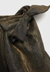 Sort og guld tekstureret stof med en dekorativ knude-detalje. Overfladen har en shimmerende, metallisk finish og et flydende design.