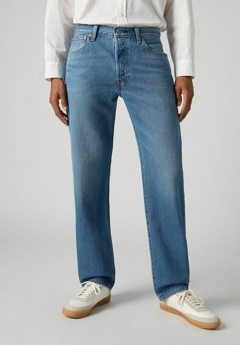 Jeans de mezclilla azul claro con corte recto, que presentan sutiles rayas verticales, cinco bolsillos y un cierre tradicional de botón y cremallera.