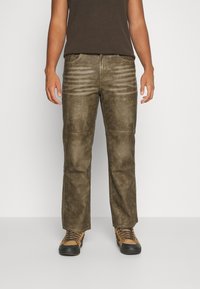 Olivgrön cargobyxor med en lätt glänsande yta, med horisontella sömmar på framsidan och sidofickorna.