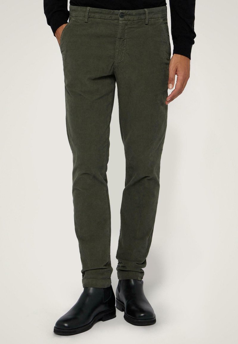 Olivgröna byxor i slim fit-design, tillverkade av bomullstyg med struktur. Matchas med svarta ankelboots med en slät yta.