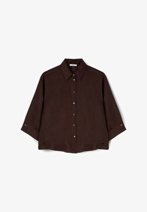 Camisa marrón oscuro abotonada, con mangas largas, cuello clásico y dobladillo ligeramente redondeado sobre fondo blanco.