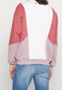 Felpa con maniche lunghe, design a blocchi di colore in bianco, rosa e lavanda, e finitura testurizzata. Vestibilità rilassata con polsini a costine.