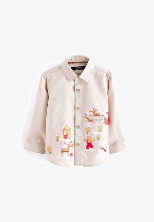 Camisa beige para niños con botones y estampados navideños que incluyen a Papá Noel, renos, hombre de jengibre, muñeco de nieve y árboles nevados.