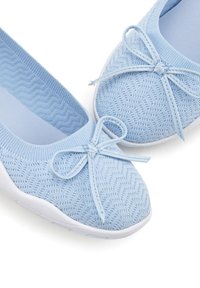 Scarpe lavorate a maglia azzurro chiaro con un motivo testurizzato, punta arrotondata e suola in gomma bianca. Presentano un fiocco decorativo nella parte anteriore.