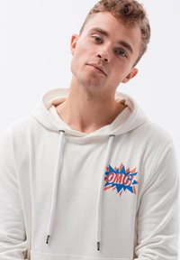 Sudadera blanca de tela suave, con un gráfico colorido de "OMG!" en la parte frontal, que presenta acentos en azul, naranja y rojo.