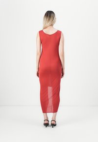 Rød ermeløs maxikjole med en tettsittende design, som har en rund halslinning og en vertikal splitt detalj bak. Glatt, lett stoff.