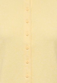 Cardigan jaune en maille douce avec une patte de boutonnage comportant six boutons assortis et une texture subtile sur tout le tissu.