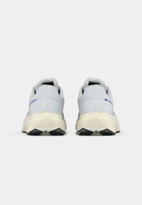 Baskets de sport gris clair avec un dessus en mesh texturé, un col rembourré et une semelle intermédiaire blanche. Dotées d'une semelle extérieure en caoutchouc noir durable et d'accents bleus.