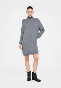 Hallide hallide kaelusega hall kudum dress, pikad varrukad, lõdvestunud istuvus, keskmise reie pikkus, koos mustade pahkluu saapadega, millel on metallik aktsendid.