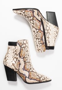 Botas de tobillo de piel de serpiente con cierre de cremallera negra, que presentan una superficie texturizada, tacón cuadrado y un diseño de punta afilada en colores neutros.