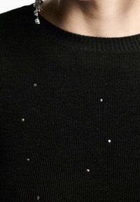 Suéter negro de punto con cuello acanalado, que presenta pequeños adornos plateados dispersos para un detalle añadido.