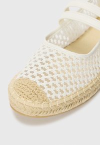 Espadrille en maille blanche avec une semelle en jute tissée, un bout arrondi et deux lanières sur le dessus pour un maintien sûr.