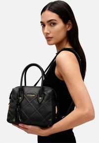 Borsa a tracolla in pelle nera trapuntata con doppi manici superiori, dettagli in metallo dorato e tracolla removibile, decorata con un nappina.