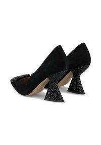 Scarpe con tacco alto in suede nero con punta affusolata, caratterizzate da accenti di gioielli sulla punta e un tacco decorato con forma unica.