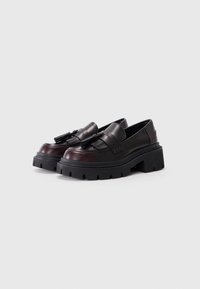 Loaferi din piele negre și burgundy, cu o talpă groasă și detalii cu ciucuri. Textură netedă, formă rotundă și accente decorative prin cusături.