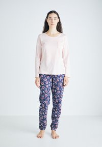 Ljust rosa långärmad topp med ficka, i kombination med marinblå blommönstrade byxor. Mjuk tyg, avslappnad passform och elastiska manschetter vid anklarna.