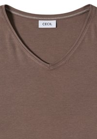 T-shirt marron à col en V avec des coutures visibles autour du col et une étiquette blanche portant l'inscription "CECIL" au dos du col.
