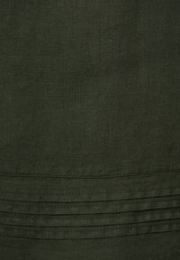 Dunkelgrüner Leinenstoff mit glatter Textur, der subtile horizontale Falten entlang der unteren Kante aufweist.