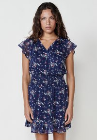 Rochie florală de culoare bleumarin, cu mâneci scurte și fluturate, decolteu în V și talie elastică, având o fustă fluidă cu volan la tiv.