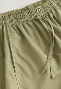 Olivenfarvede shorts med elastisk talje og snørelukning, fremstillet i glat stof med sidesømme og blød tekstur for komfort.