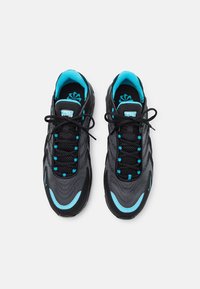 Svarta träningsskor med en texturerad överdel, prydda med akvamarinblå detaljer längs snörena, tungan och sidorna. Standard snörningsdesign.