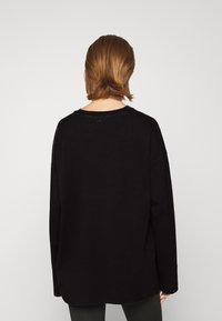 Mustat ylisuuret collegepaidat, joissa on pyöreä kaula-aukko ja pitkät hihat, valmistettu pehmeästä kankaasta, rento malli ja suora helma.