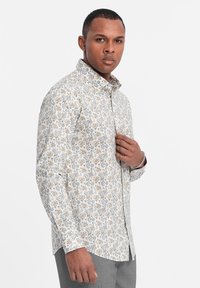Langærmet skjorte med hvid bundfarve og blomsterdesign i orange, gul og grå. Knap-ned krave og normal pasform.