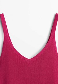 Débardeur ajusté en maille de couleur magenta vif, avec fines bretelles et un décolleté en V. La texture est côtelée, offrant une élasticité douce.