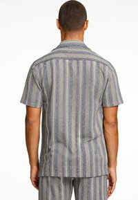 Camicia a maniche corte in tessuto a righe blu e grigie, con colletto e orlo dritto. La texture è tessuta con motivi verticali.