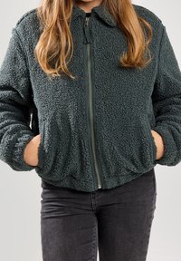 Dark green, fuzzy-textured zip-up jacket with a rounded collar and side pockets; features elastic cuffs and a relaxed fit.