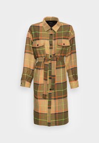 Długa koszulowa sukienka w kratę w kolorach brązowym, zielonym, pomarańczowym i żółtym. Zawiera zapięcie na guziki, dwie kieszenie na piersiach oraz pasujący pasek do przewiązywania.