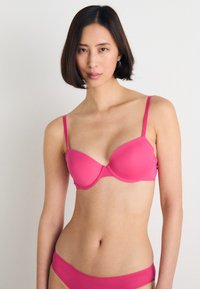 Sutiã rosa com aros, copas lisas, alças ajustáveis e um modelo de biquíni combinado, apresentando um design sem costuras e minimalista.