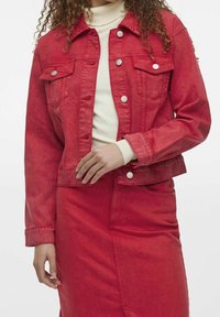 Rød denimjakke med knapper foran, to brystlommer og en cropped pasform. Stoffet ser let slidstærkt ud med synlige sømme.