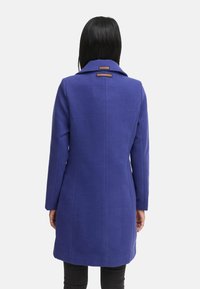 Mid-length coat in vibrant purple fabric, single-breasted design with a notched collar and two decorative labels on the back.