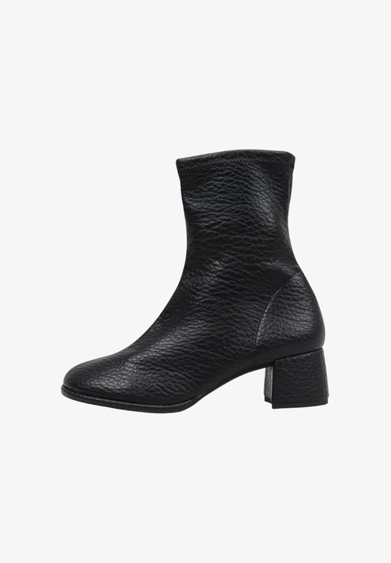 Bottine noire en cuir avec une finition texturée, un bout carré et un petit talon carré. Les coutures ajoutent de la structure au design.