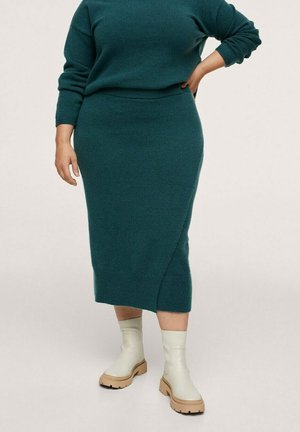 Jersey de punto color verde azulado y falda lápiz midi, con una abertura lateral. Combinado con botines de suela gruesa en color claro. Textura suave en general.