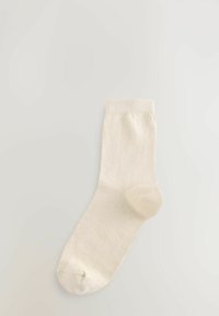 Kreminės spalvos kulkšninės kojinės, pagamintos iš minkštos, tekstūruotos medžiagos, su besiūle pirštine ir ribotu užlenkimu. Paprastas dizainas, tinkantis kasdieniam nešiojimui.