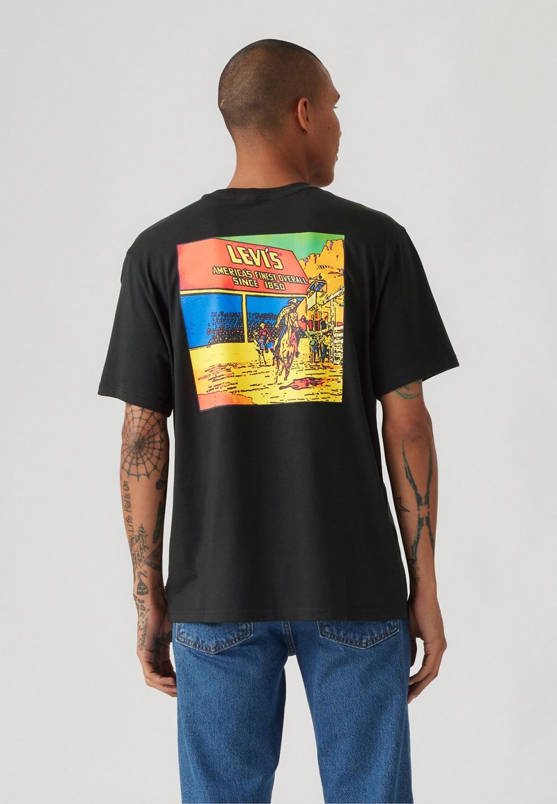 Svart bomulls t-skjorte med et fargerikt grafisk motiv på baksiden som skildrer en vestlig scene, med "LEVI'S" og tekst i fete bokstaver.