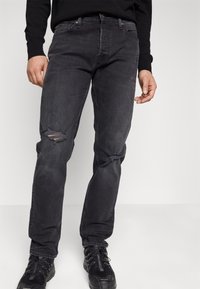 Svarta jeans med avslappnad passform, med rivna knän, detaljerad sömnad och klassisk femficksdesign. Perfekta för avslappnat bruk.