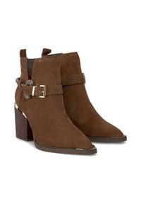 Botas de tobillo de ante marrón con punta afilada, detalle de hebilla plateada, acentos texturizados y tacón apilado. Presentan un acabado suave y mate.