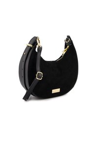 Schwarze Wildlederhandtasche mit geschwungenem Design, goldenen Beschlägen, abnehmbarem Schulterriemen und einem Reißverschluss mit einem kleinen Markenplättchen.