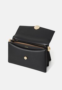 Svart läderhandväska med ett lås i guld, som har en strukturerad design och inre fack, inklusive ett zip-fack.