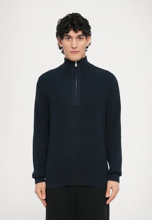 Pull en maille côtelée bleu marine avec col montant et fermeture éclair au quart. Caractérisé par des manches longues et une coupe décontractée, confectionné dans un tissu doux et texturé.