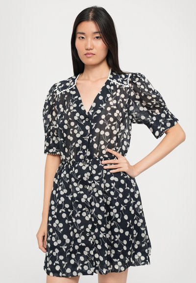 Rochie scurtă bleumarin cu un model floral alb, mâneci puff și închidere cu nasturi în față. Prezintă un guler cu dantelă și talie strânsă.