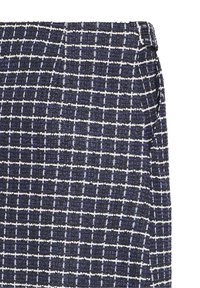 Tissu en tweed à carreaux bleu marine et blanc sur une jupe droite avec une fente latérale.
