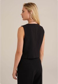 Juodas be rankovių topas, pagamintas iš tekstūruoto audinio, turi prigludusią fasoną ir apvalų iškirpimą, su lygiu nugaros pjūviu ir švelniais siūlais.