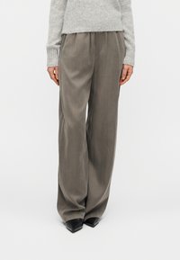 Grey wide-leg trousers with a soft texture, featuring pleats at the front, paired with pointed black shoes and a light grey sweater.